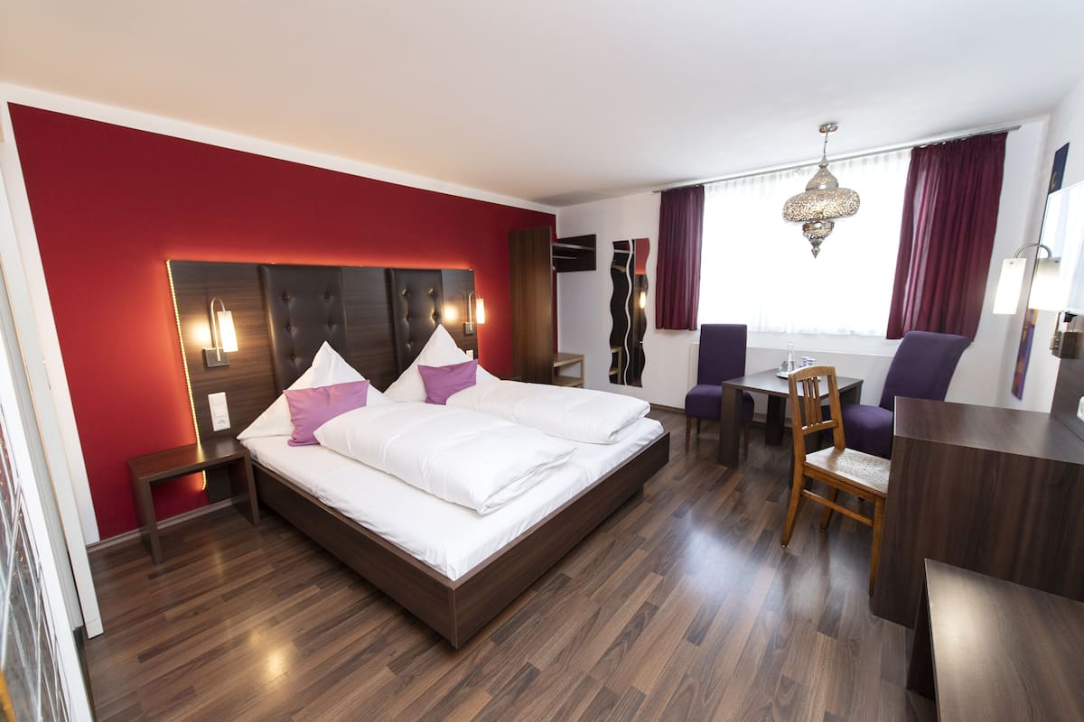 A hotel room with a large bed, a desk, and a chair.