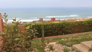 A coastal view with a garden, a cactus, and a building with a red roof. - Charming villa facing the sea. (province chtouka Ait Baha)