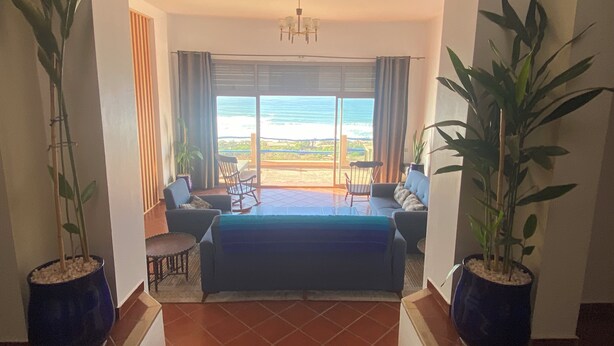 A room with a large bed, two chairs, a table, and a view of the ocean. - Charming villa facing the sea. (province chtouka Ait Baha)