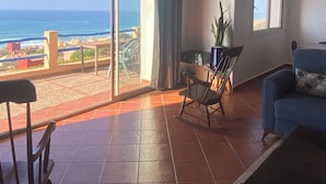 A spacious living room with a view of the ocean, a balcony with a table and chairs, and a blue sofa. - Charming villa facing the sea. (province chtouka Ait Baha)