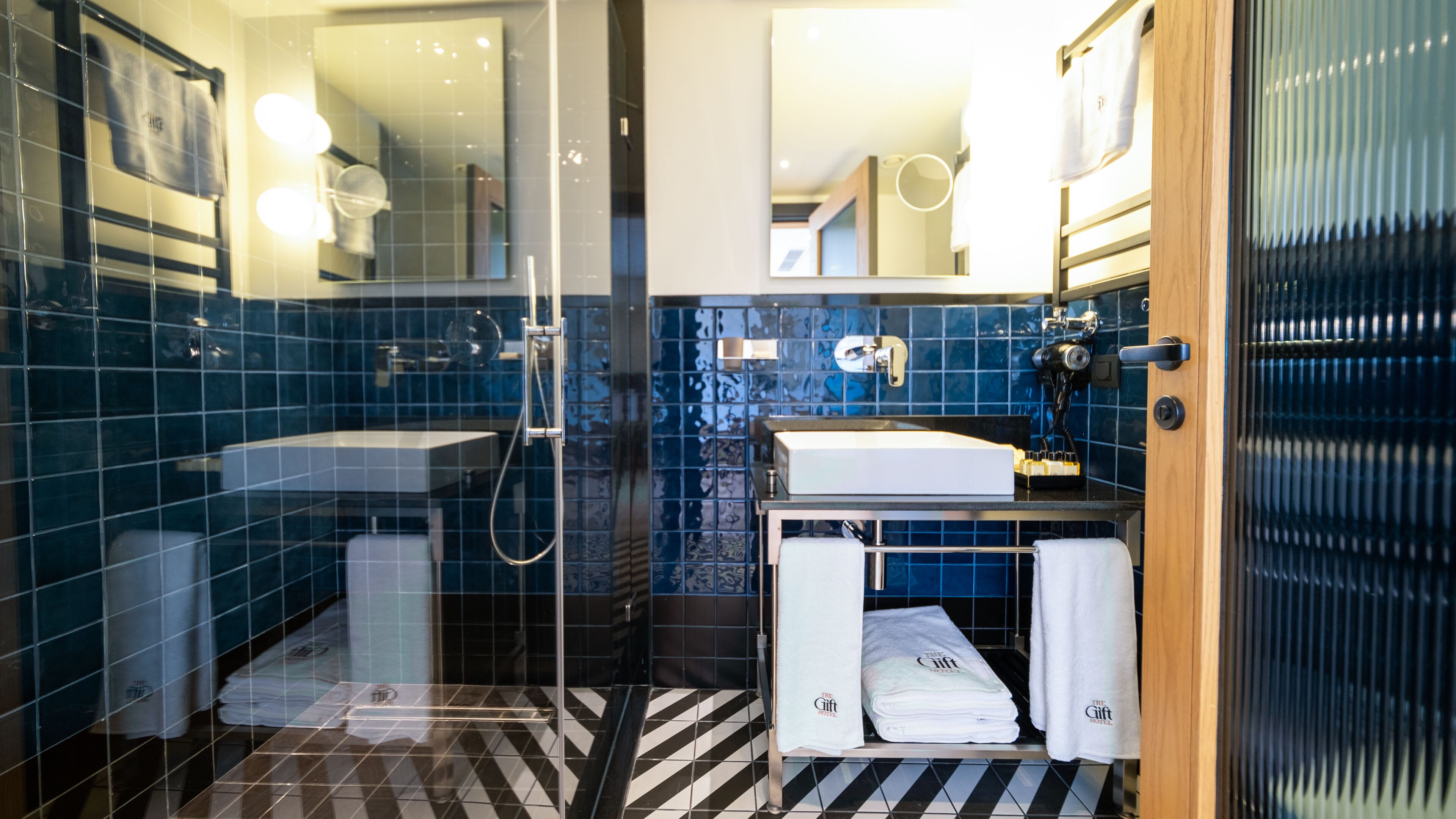 A modern bathroom with a glass shower enclosure, a sink, and a vanity with a towel rack.