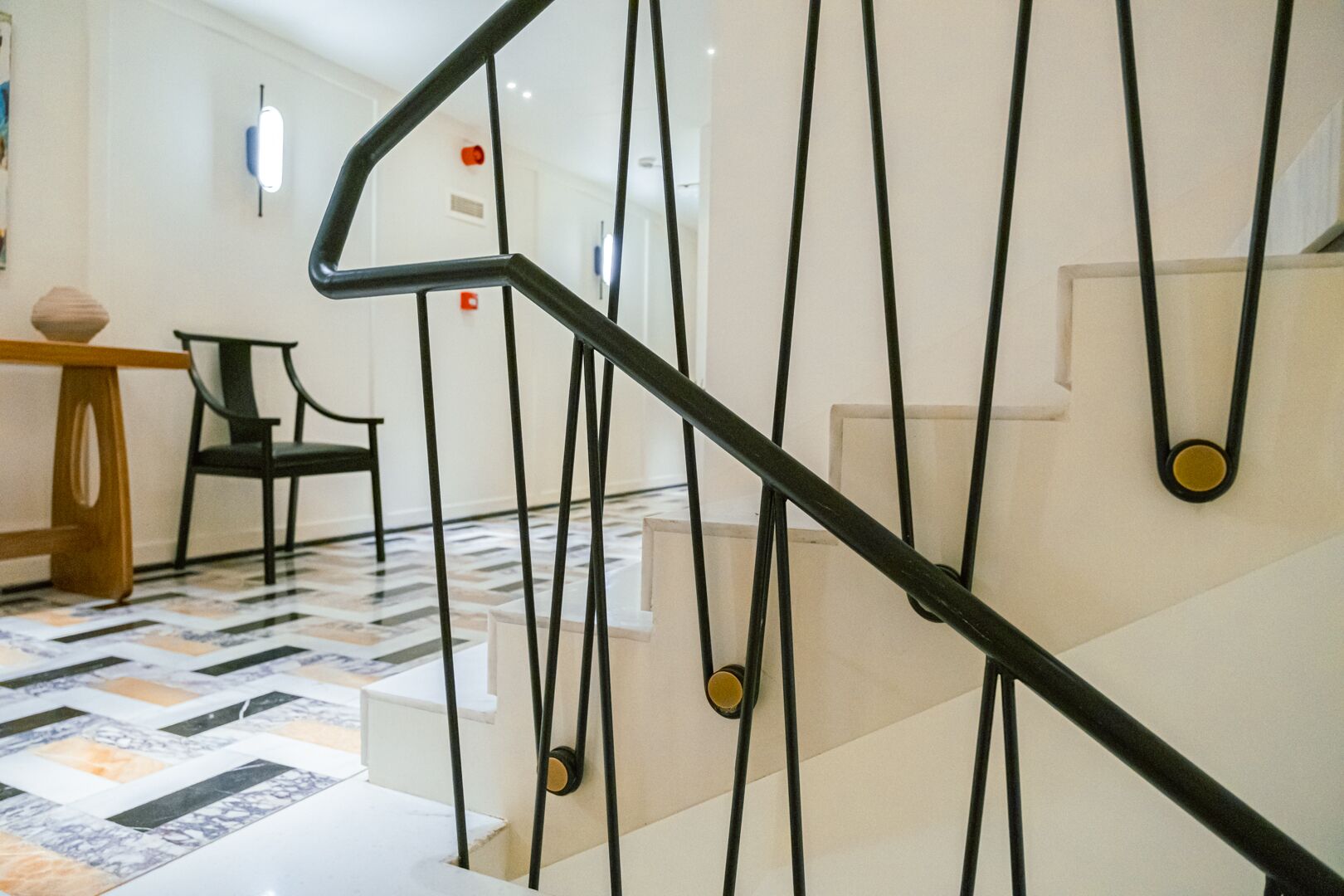 A modern staircase with black metal railings and a patterned floor.