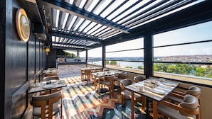 A restaurant with outdoor seating, a view of the city, and a modern interior design. - The Gift Hotel (Istanbul)