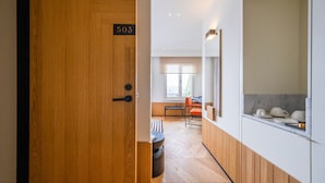 A modern interior with a wooden door marked '503', a kitchen area with marble countertops, and a dining space with a window and orange chairs. - The Gift Hotel (Istanbul)