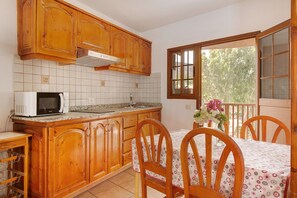 A kitchen with wooden cabinets, a microwave, and a dining area with a table and chairs.