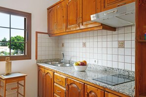 A kitchen with wooden cabinets, a granite countertop, a stainless steel sink, and a window with a view of trees. - Holiday Home 'Cottage Santa Lucía 2' with Mountain View, Balconies & Wi-Fi (Santa Lucía de Tirajana)