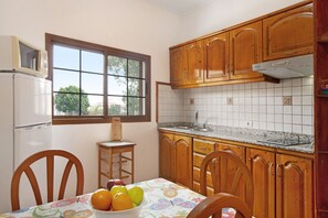 A kitchen with wooden cabinets, a window, a sink, and a table with chairs.
