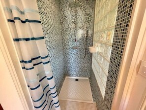 Shower area features a single showerhead and a non-slip mat.