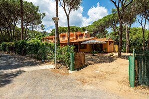 Una villa con techo de tejas, rodeada de árboles y un camino de grava.