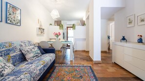 A modern living room with a sofa, dining area, and kitchen. - Holiday Home 'Villetta Pineta' with Private Garden (Santa Margherita di Pula)