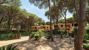 A courtyard with trees, a dirt path, and buildings with a uniform architectural style. - Holiday Home 'Villetta Pineta' with Private Garden (Santa Margherita di Pula)