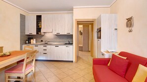 Ein kompakter Wohnraum mit Küche, Essbereich und einem roten Sofa.