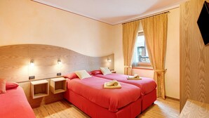 Ein Hotelzimmer mit zwei Betten, einem Holzkopfende, Nachttischen und einem Fenster mit Vorhängen.