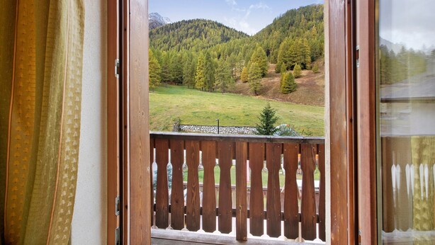 Un balcón de madera con vistas a un paisaje verde y montañas.