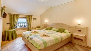Un dormitorio con una cama de madera, una mesita pequeña, una silla y una ventana con cortinas.