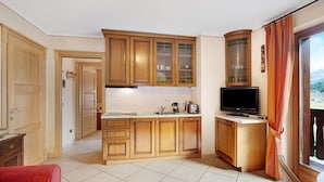 Una cocina con armarios de madera, un televisor y una ventana con cortinas.
