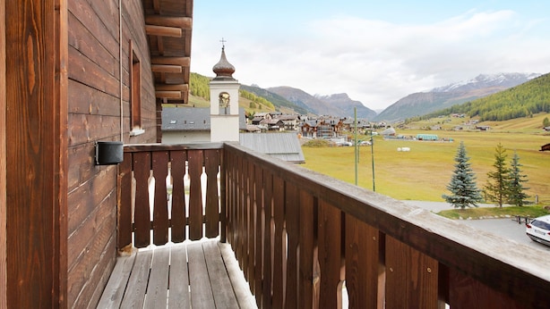 Un balcón de madera con vistas a un pueblo y montañas.