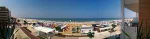 A beachside view with a large number of umbrellas and beach chairs, a playground, and a building with the number 96. - Hotel RECORD (Riccione)