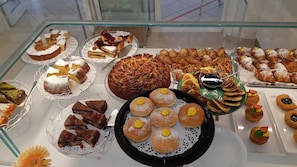 A variety of pastries and desserts displayed on glass shelves. - Hotel RECORD (Riccione)