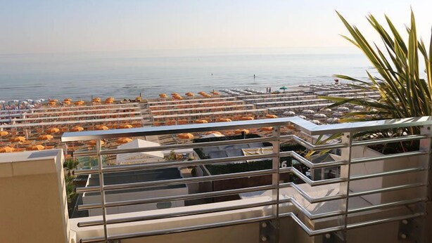 Un balcón de hotel con vista al mar y sombrillas de playa.