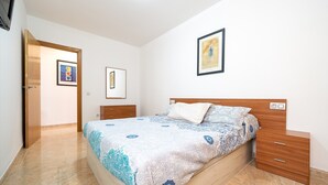 A bedroom with a bed, wooden nightstands, a door, and framed artwork on the wall.