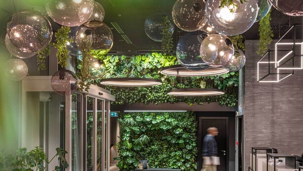 A modern lobby with a green wall, hanging spherical lights, and a bench. - J44 Lifestyle hotel (Jesolo)