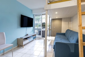 A living room with a TV mounted on the wall, a sofa, a small table, and a wooden bench.