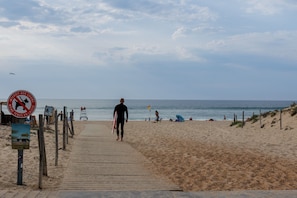 Een strand met een houten looppad naar de zee, een uitkijktoren voor de strandwacht en een bord met daarop 'zwemverboden'.