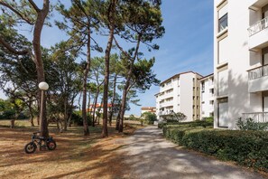Un sendero conduce a un edificio con varios balcones, rodeado de árboles y una bicicleta estacionada.
