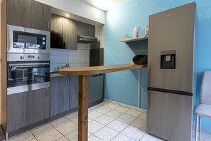 Una cocina moderna con electrodomésticos de acero inoxidable, una mesa de madera y un dispensador de agua.