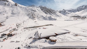 Eine verschneite Berglandschaft mit Skipisten, einer Seilbahn und einer kleinen Berghütte.