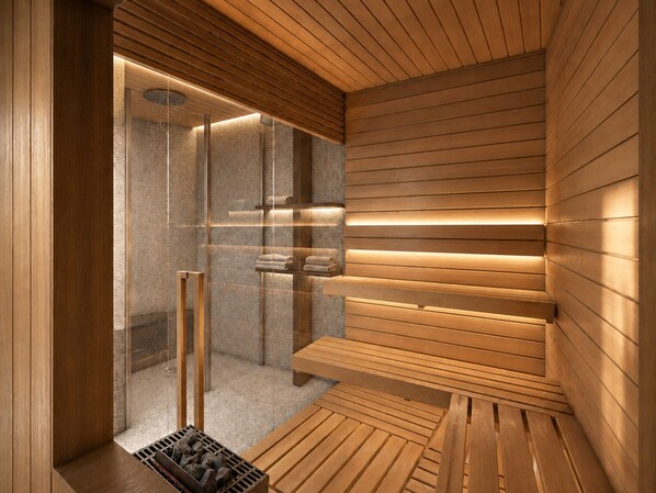 A sauna with wooden walls and benches, a glass door, and a bench with towels.