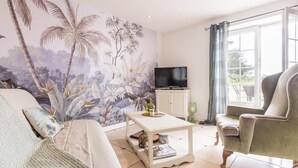 A living room with a large mural, a television, a coffee table, and a sofa.
