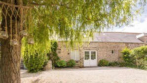 A stone building with a gravel driveway, a tree with hanging glass ornaments, and a white door.