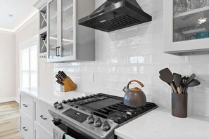 Una cocina moderna con estufa a gas, electrodomésticos de acero inoxidable y hervidor.