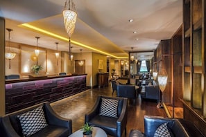 Un vestíbulo de hotel con mostrador de recepción, zona de estar y bar.