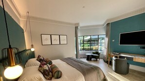 A modern hotel room with a large bed, a desk, and a TV.