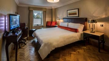 Una habitación de hotel con una cama grande, televisión, escritorio y lámpara.