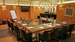 A conference room with a long table, chairs, a whiteboard, and a television.