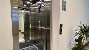 A modern elevator with a stainless steel finish, a digital display, and a potted plant beside it. - Hotel Globo (Durrës)