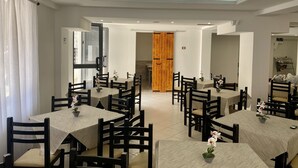 A dining area with multiple tables and chairs, a wooden door, and a ceiling with a leaf pattern. - Hotel Globo (Durrës)