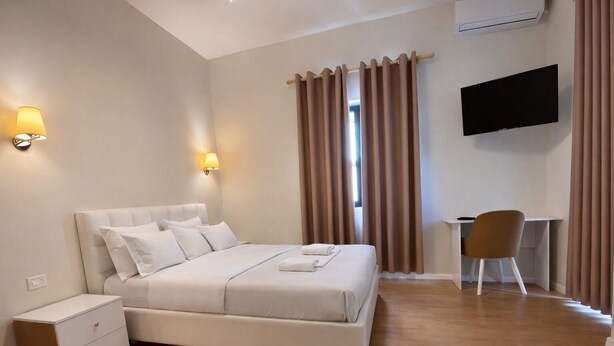 A modern bedroom with a large bed, bedside lamps, a desk, and a TV. - Hotel Globo (Durrës)