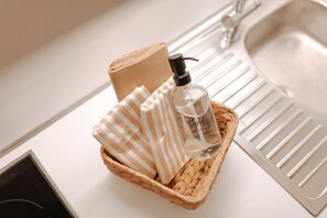A bathroom sink with a soap dispenser and a striped towel in a basket.
