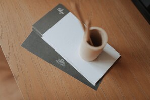 A wooden table with a white envelope and a small ceramic cup.