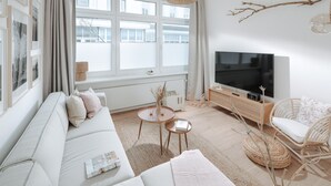 Una sala de estar moderna con un sofá, televisor y muebles de mimbre.