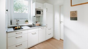 A modern kitchen with white cabinets, a microwave, and a sink. - // V I L L A F R E S E N A // Bude 3 (Norderney)