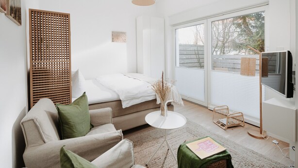 A modern living room with a sofa, a coffee table, and a TV. - // V I L L A F R E S E N A // Bude 3 (Norderney)