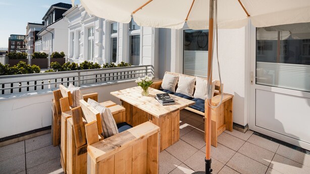 A rooftop terrace with wooden furniture, a table, and a white umbrella. - // V I L L A F R E S E N A // Bude 6 (Norderney)