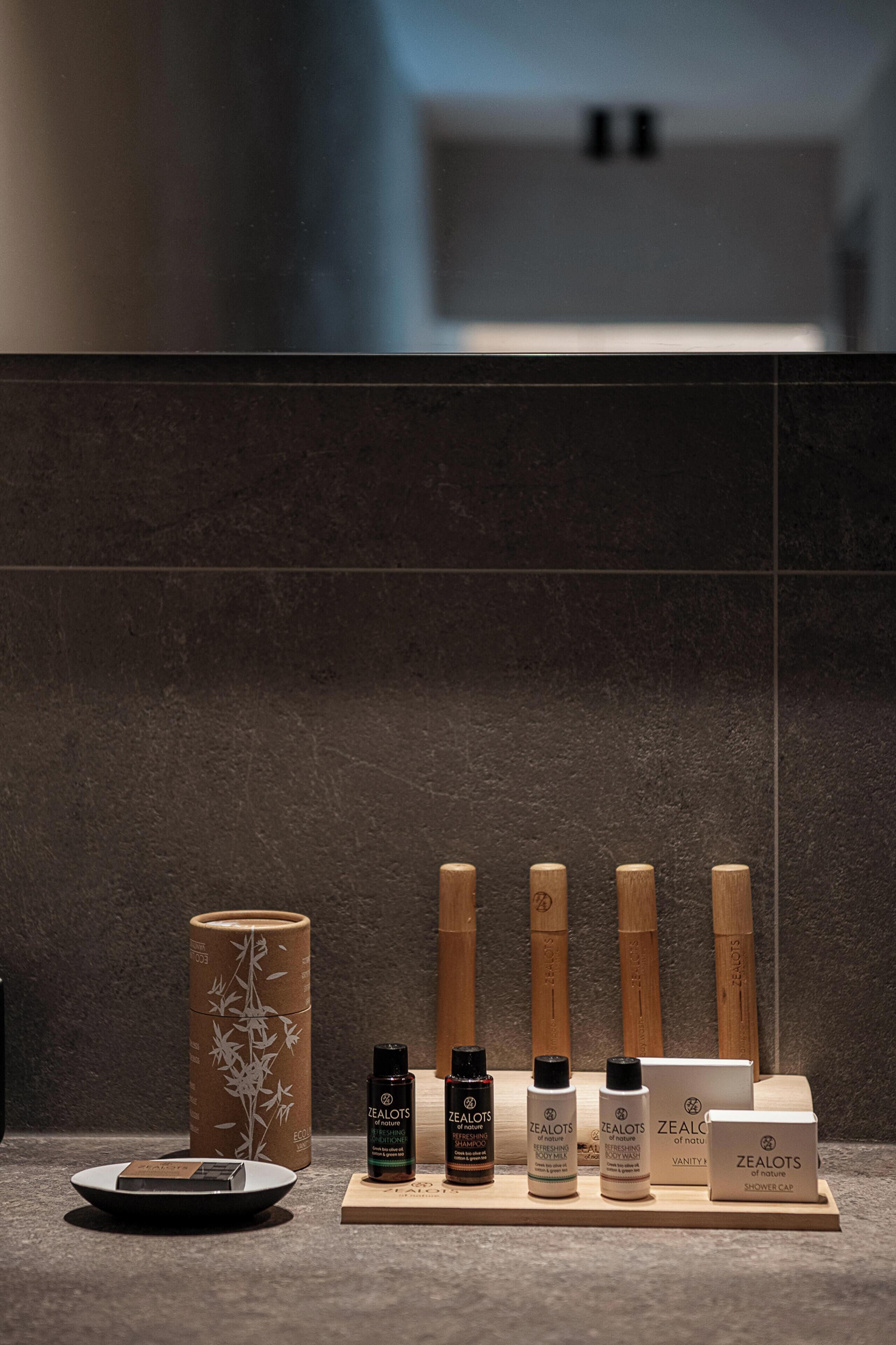 A display of Zealots products including a cylindrical container, bottles, and a box on a wooden stand.