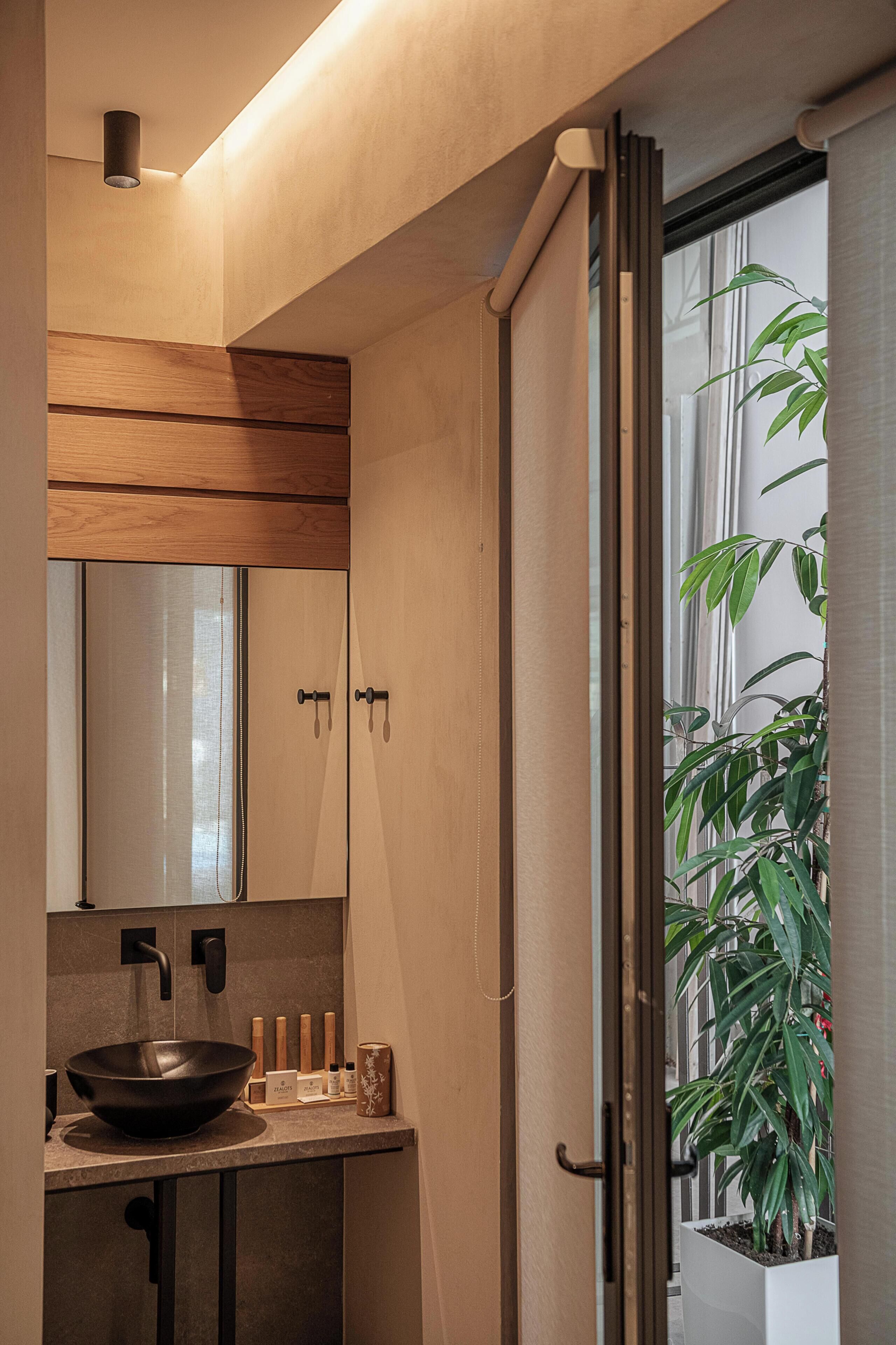 A modern bathroom with a wooden vanity, a black sink, and a large mirror.